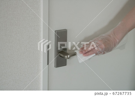 ドアノブを除菌シートで拭くビニール手袋をつけた女性の手元 67267735