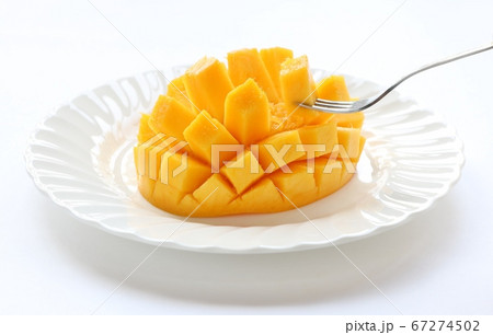 円い白皿の上の花咲状にカットしたマンゴー　フォークあり 67274502