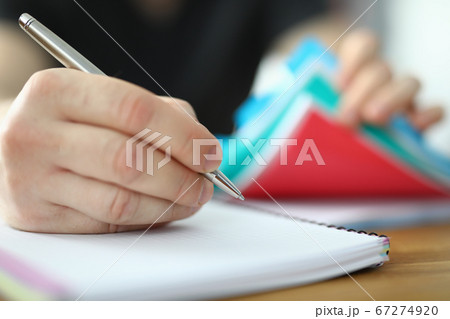 Man holds pen in his hand and writes in notebook 67274920