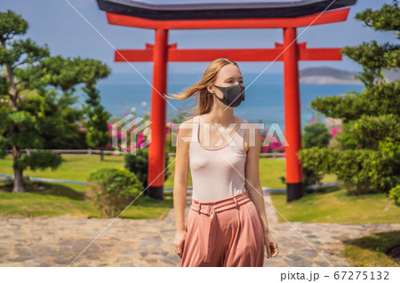 traveler in medical mask stopped on the street and looking at the Japanese traditional building. Tourists travel in Japan after the coronavirus epidemic traveler in medical mask stopped on the street and looking at the Japanese traditional building. Tourists travel in Japan after the coronavirus epidemic 67275132