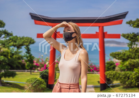 traveler in medical mask stopped on the street and looking at the Japanese traditional building. Tourists travel in Japan after the coronavirus epidemic traveler in medical mask stopped on the street and looking at the Japanese traditional building. Tourists travel in Japan after the coronavirus epidemic 67275134