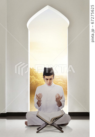 Asian Muslim man sitting while raised hands and 67275625