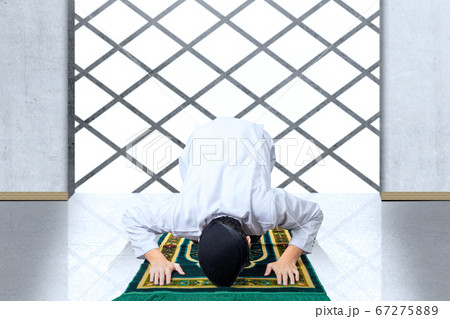 Asian Muslim man with a prayer rug in a praying 67275889