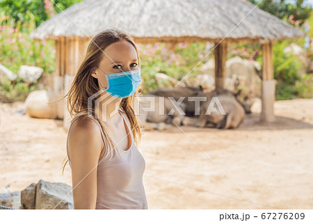 Young woman at the zoo in a medical mask. Visiting public places after the coronavirus epidemic 67276209