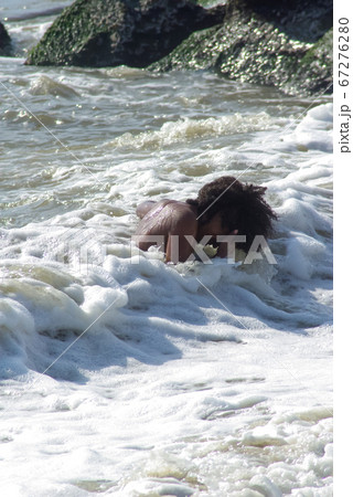 Solitary young boy laughs while playing in the ocean waves. Solitary young boy laughs while playing in the ocean waves. 67276280