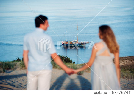 A couple in love stands on the beach in the dunes against the background of the Baltic sea and a ship, a Couple on the beach close-up in Lithuania, Nida 67276741
