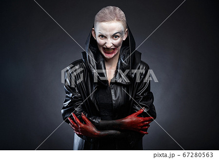 Photo of horror woman in black leather raincoat with red hands 67280563