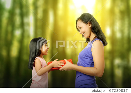 Asian little girl giving her mother a gift box Asian little girl giving her mother a gift box 67280837