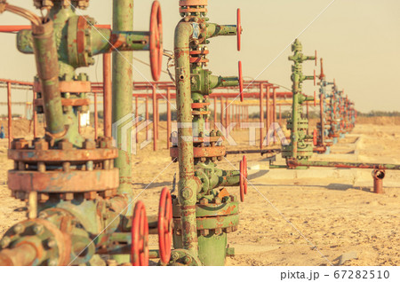 Petroleum well wellhead equipment. Hand valve with handwheel on the flow line. Oilfield site. Oil, gas industry concept. Industrial site background. Production oil. Multiple check valve gate armature. Petroleum well wellhead equipment. Hand valve with handwheel on the flow line. Oilfield site. Oil, gas industry concept. Industrial site background. Production oil. Multiple check valve gate armature. 67282510