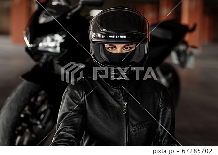 Horizontal shot of unrecognizable woman motorcycle rider driving her enduro motobike or chopper dressed in stylish leather clothes and protective equipment, blurred ligths and cars in background Horizontal shot of unrecognizable woman motorcycle rider driving her enduro motobike or chopper dressed in stylish leather clothes and protective equipment, blurred ligths and cars in background 67285702