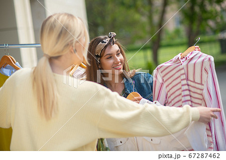 Nice young women discussing which clothes to buy Nice young women discussing which clothes to buy 67287462