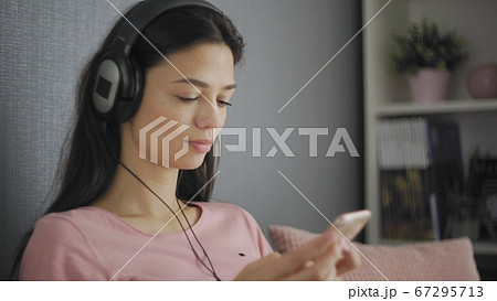 Happy teen listening to music relaxing on a sofa at home Happy teen listening to music relaxing on a sofa at home 67295713