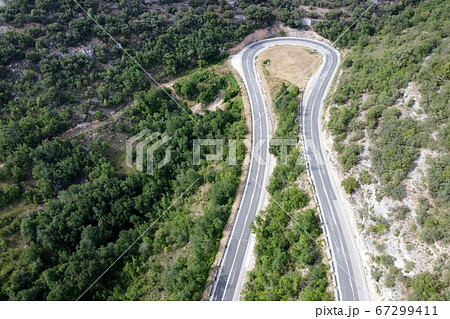 Aerial view of winding road in high mountain pass trough green pine woods. 67299411