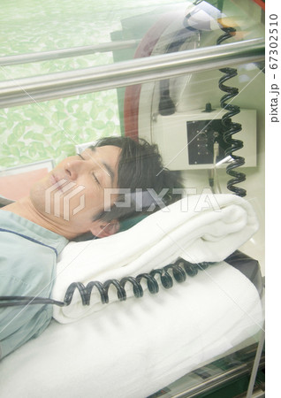 酸素カプセルに入る男性 67302510