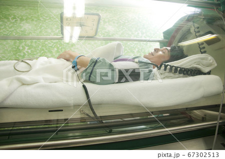 酸素カプセルに入る男性 67302513