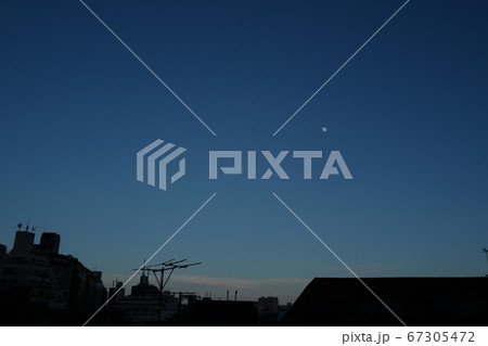 夕暮れの空に浮かぶ月と都心の街並み 67305472