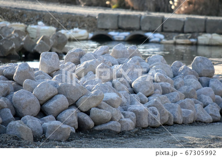 河川工事中の川べりに積まれた沢山の白く丸っぽい石 河川工事中の川べりに積まれた沢山の白く丸っぽい石 67305992