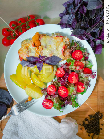 Prepared French style meat dish with potato slices and cherry tomatoes 67308371