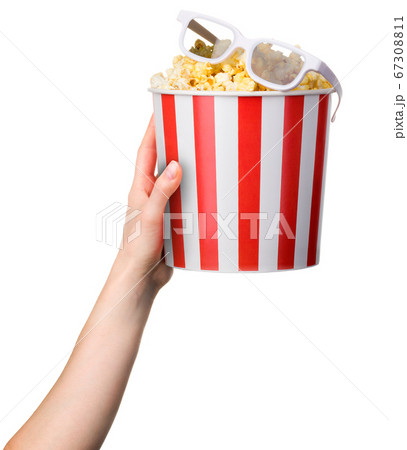 Woman hand holding striped bucket with popcorn and 3D glasses isolated on white Woman hand holding striped bucket with popcorn and 3D glasses isolated on white 67308811