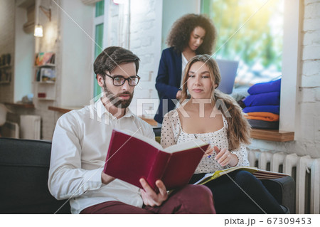 Bearded guy reading book and two girls. Bearded guy reading book and two girls. 67309453