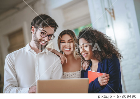 Man with laptop and two girls looking at screen Man with laptop and two girls looking at screen 67309490