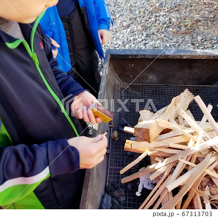 [火育] マッチで薪に火をつけようとする子供[体験学習] 67313703