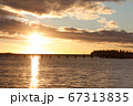 夕日を背景に島に続く橋をジョギングして渡る女性 67313835