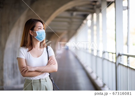 Young Asian woman wearing surgical mask walking in city 67316081