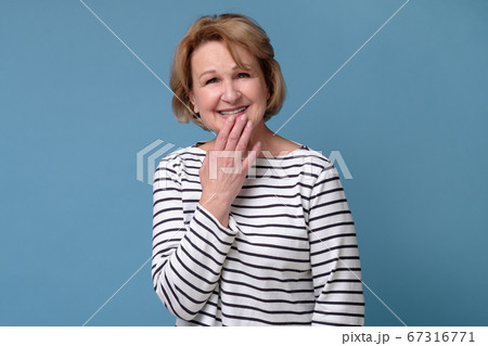 Mature caucasian woman laughing covering mouth with hand. 67316771