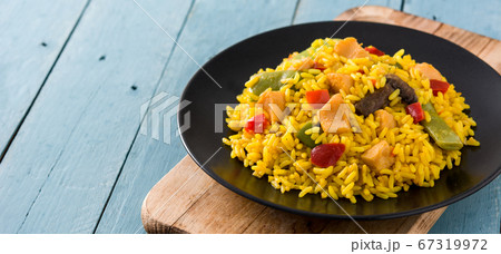 Fried rice with chicken and vegetables on black plate on blue wooden table. Copy space Fried rice with chicken and vegetables on black plate on blue wooden table. Copy space 67319972