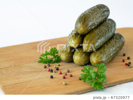 Healthy fermented sliced gherkins or cucumbers with herbs and spices on rustic wooden board isolated on white 67320977