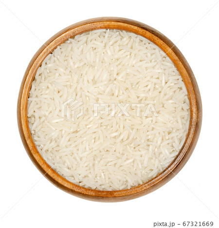 White Basmati rice in wooden bowl. Rice variety with long, slender grains and aromatic smell and taste, traditionally from Indian subcontinent. Closeup from above over white isolated macro food photo. 67321669