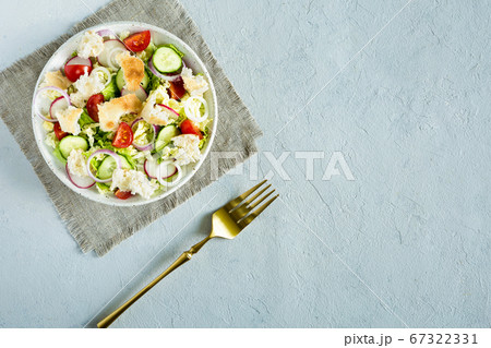 Salad fattoush. Healthy vegetarian food. Traditional Middle Eastern salad with with pita bread and vegetables in the white plate on the light background. Close up, top view, copy space, flat lay. 67322331