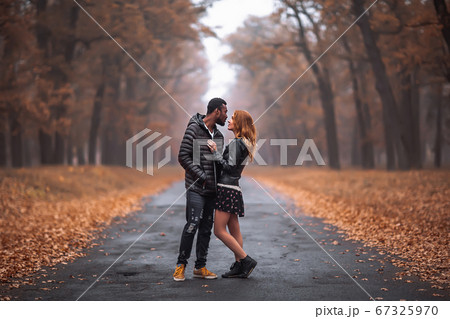 Interracial couple posing in autumn park road 67325970