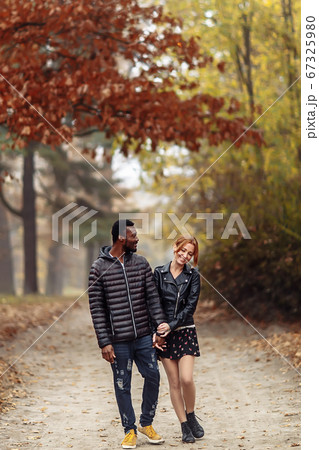 Happy interracial couple walking in autumn park 67325980