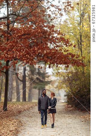 Happy interracial couple walking in autumn park 67325981