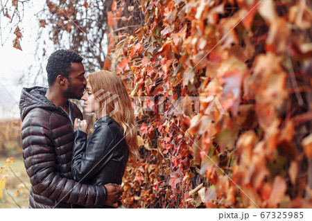 Interracial couple posing in autumn leaves Interracial couple posing in autumn leaves 67325985