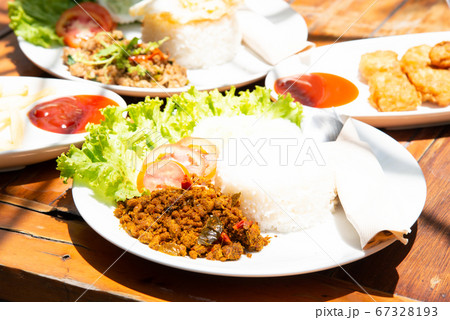 yellow curry mince prok stir fry with rice and tomato cucamber salad with another food on white plate and wood table stock photo yellow curry mince prok stir fry with rice and tomato cucamber salad with another food on white plate and wood table stock photo 67328193