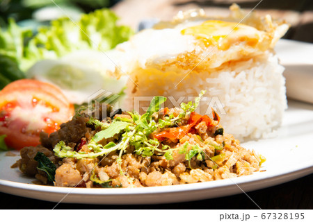 basil stir fry rice with vegetable tomato cucamber salad on white plate and wood table with another food stock photo 67328195