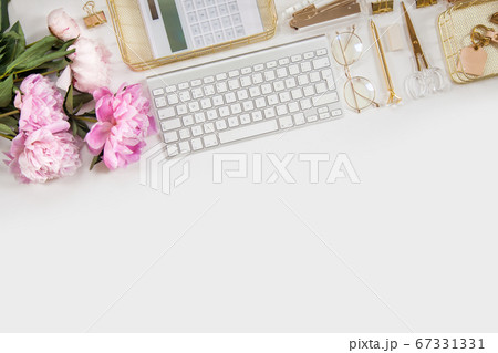 Women's diary and golden stationery. Bouquet of pink peonies. Glasses, a white keyboard, pen, scissors and coffee on the desktop. 67331331