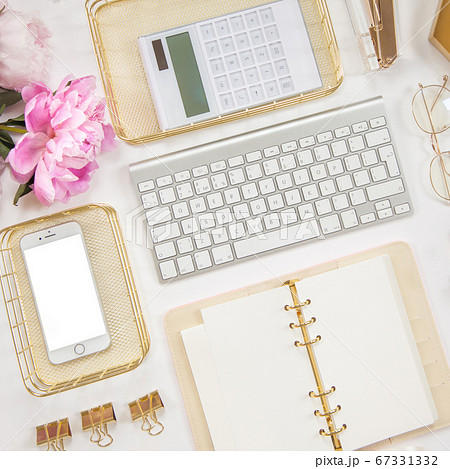 Women's diary and golden stationery. Bouquet of pink peonies. Glasses, a white keyboard, pen, scissors and coffee on the desktop. Women's diary and golden stationery. Bouquet of pink peonies. Glasses, a white keyboard, pen, scissors and coffee on the desktop. 67331332