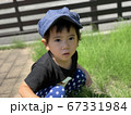 庭でしゃがんで何かをボーっと見つめる男の子 67331984