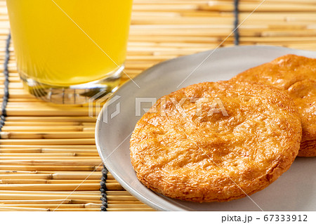 醤油せんべい。写真奥には冷たいお茶の入ったグラス。 醤油せんべい。写真奥には冷たいお茶の入ったグラス。 67333912