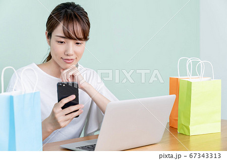 スマホとパソコンでオンラインショッピングをする若い女性 スマホとパソコンでオンラインショッピングをする若い女性 67343313