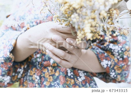 ドライフラワーと花柄のワンピースの巻き髪の女性と植物のフォトジェニックな写真の写真素材