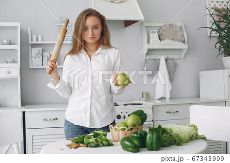 Beautiful and sporty girl in a kitchen with a vegetables Beautiful and sporty girl in a kitchen with a vegetables 67343999