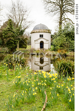 円筒とドーム型の歴史的な石造りの建物と水仙 イギリス郊外の公園にての写真素材