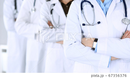 Group of modern doctors standing as a team with arms crossed in hospital office. Physicians ready to examine and help patients. Medical help, insurance in health care, best desease treatment and Group of modern doctors standing as a team with arms crossed in hospital office. Physicians ready to examine and help patients. Medical help, insurance in health care, best desease treatment and 67356376