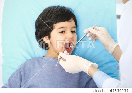Little arab boy sitting at dental chair with open mouth during oral check up while doctor. Visiting dentist office. Medicine and stomatology concept 67356537