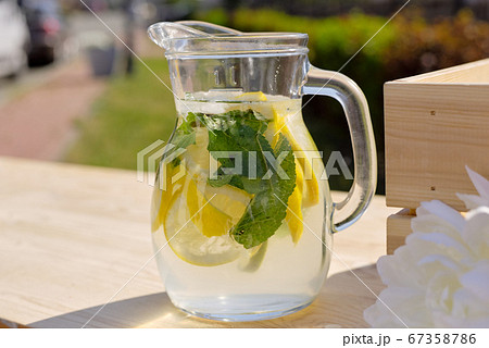Glass jug with fresh cool homemade lemonade standing on wooden market stall 67358786